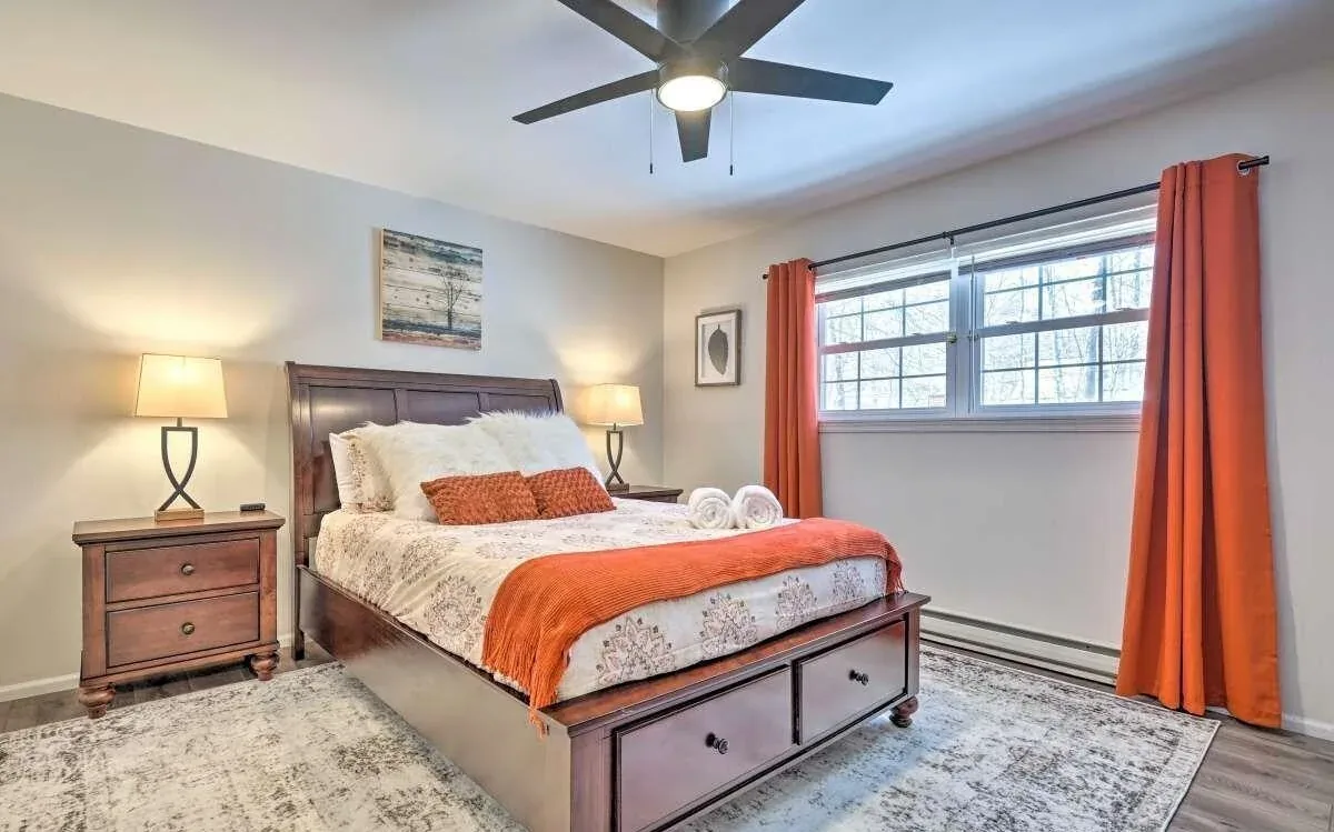 Poconos bedroom styled with warm rust accents and wood furniture