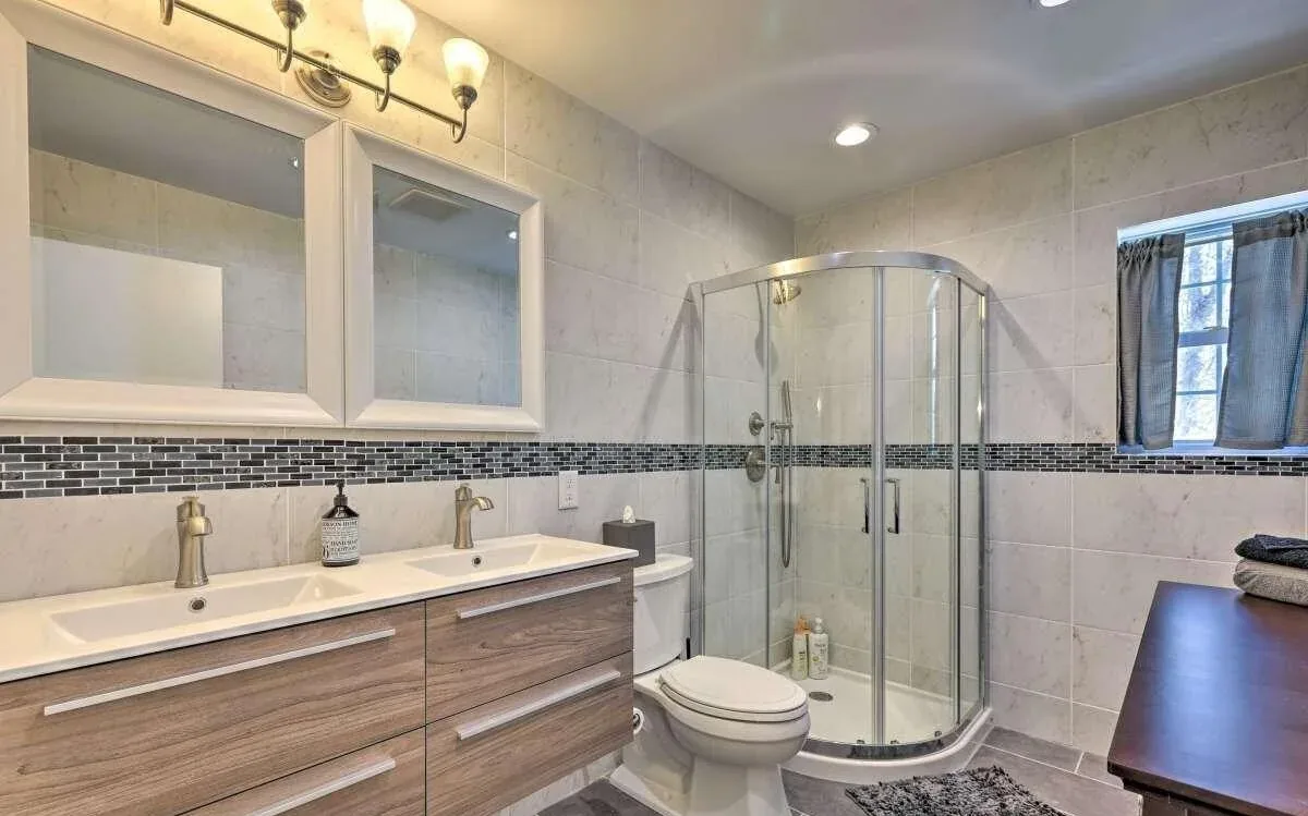Poconos remodeled bathroom with double vanity and curved glass shower