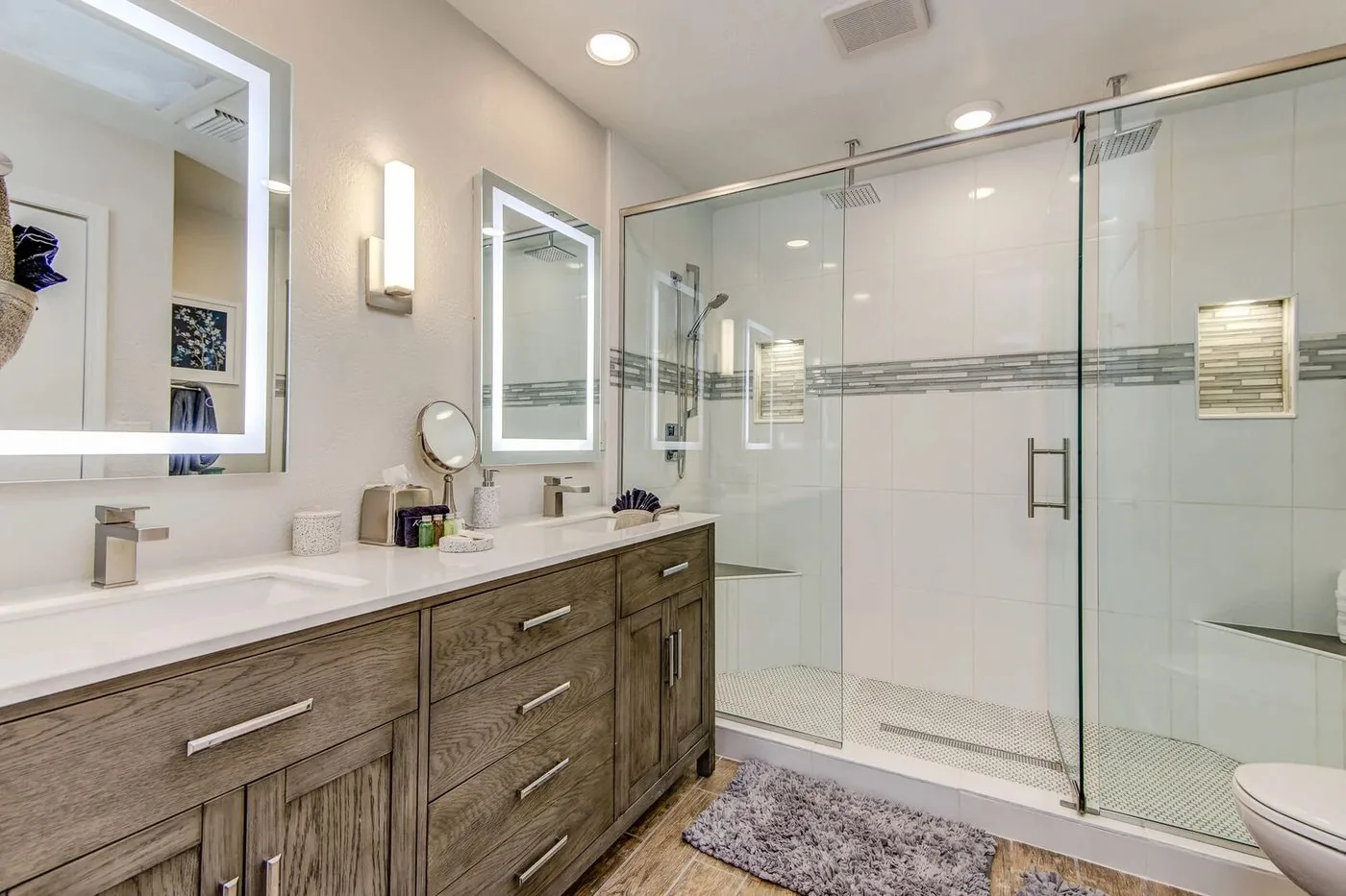 Renovated second primary bath with wood double vanity, quartz top and frameless glass shower