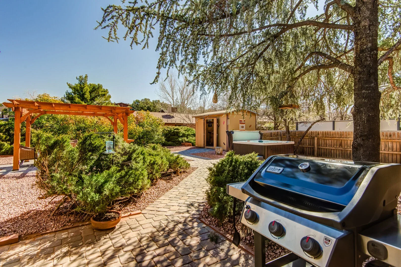 Sedona backyard with grill, pergola, hot tub, and landscaped desert setting